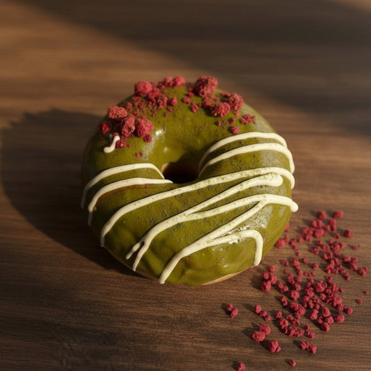 The Doughluxe Matcha White Chocolate Donut with green matcha glaze, white chocolate drizzle, and red crumble topping.